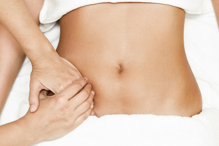 Hands massaging female abdomen Therapist applying pressure on belly