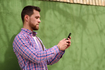 Young man looking at his smart phone in urban background  Lifest