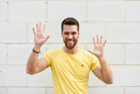 Funny young man on brick wall with open hands smiling