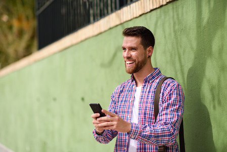 Young man laughing with his smart phone in urban background Lif