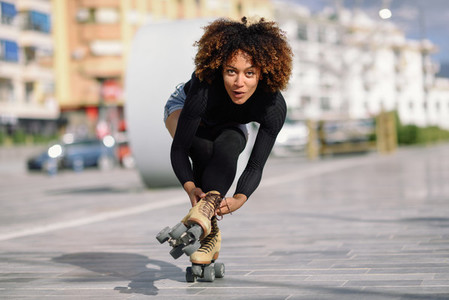 Black woman on roller skates riding outdoors on urban street