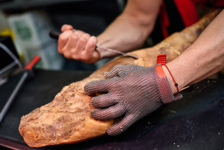 Butcher boning a ham with metal safety mesh glove