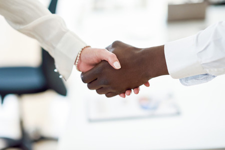 Black businessman shaking hands with a caucasian businesswoman