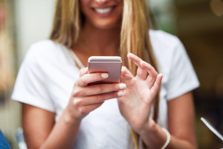 Close up image of young blonde girl texting with smartphone