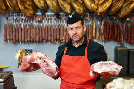 Butcher holding meat standing in a butcher shop