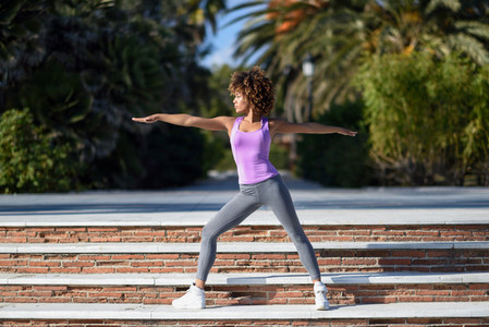 Black woman afro hairstyle doing yoga in warrior pose