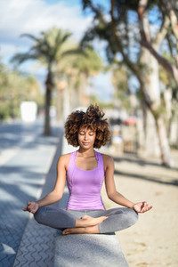 Black woman afro hairstyle in lotus pose with eyes closed in t