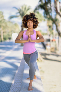 Black woman afro hairstyle doing yoga in the beach