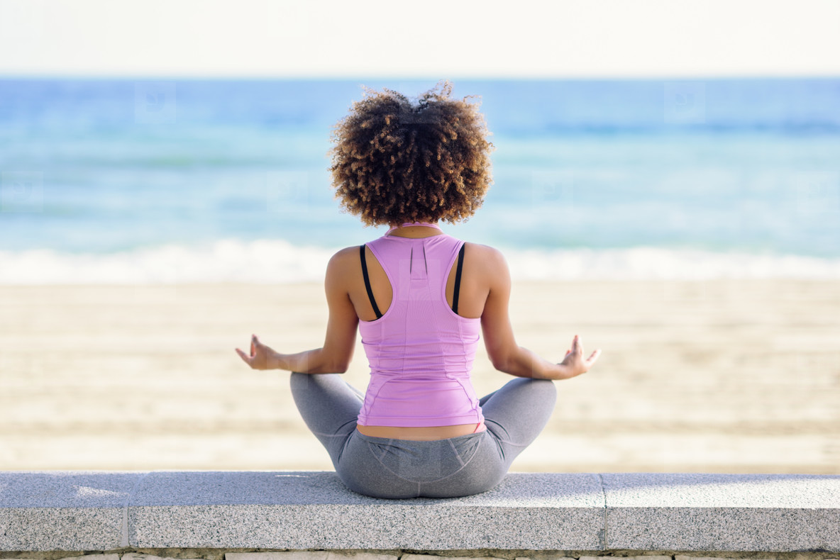 Black woman, afro hairstyle, doing yoga in the beach stock photo (183491) -  YouWorkForThem