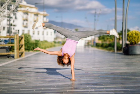 Black fit woman doing fitness acrobatics in urban background