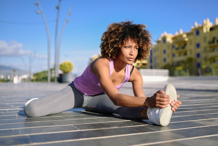 Young black woman doing stretching after running outdoors