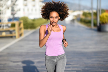 Black woman afro hairstyle running outdoors in urban road