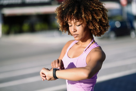 Young black woman using smartwatch touching touchscreen