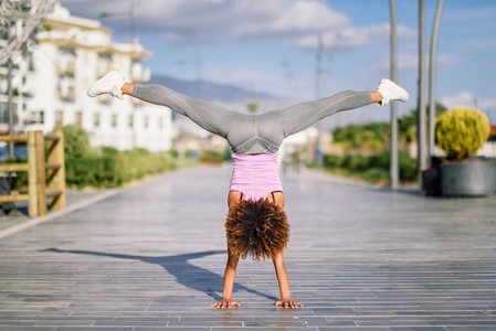 Black fit woman doing fitness acrobatics in urban background