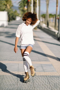 Black woman on roller skates rollerblading in beach promenade wi
