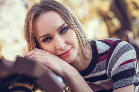 Young blonde woman sitting on a bench of a park