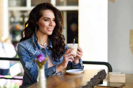 Woman sitting indoor in urban cafe wearing casual clothes