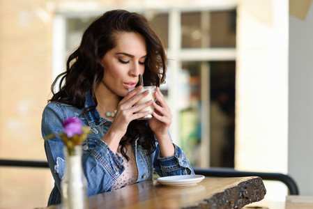 Woman sitting indoor in urban cafe wearing casual clothes