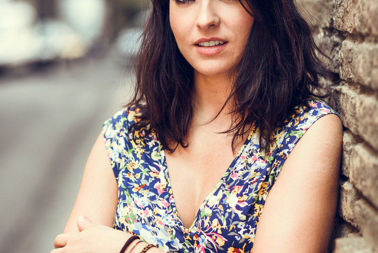 Young woman with blue eyes standing next to brick wall