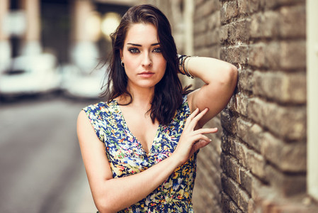 Girl with blue eyes standing next to brick wall outdoors