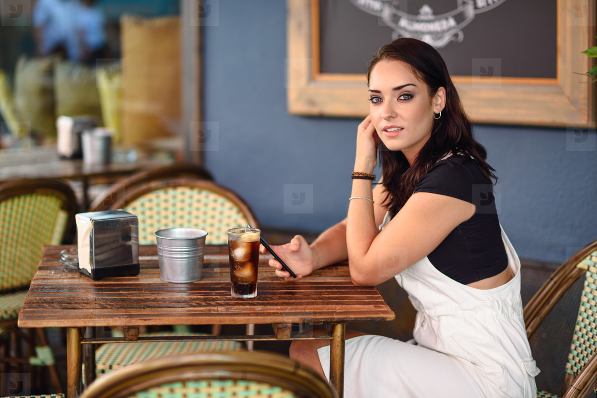 Girl with blue eyes sitting on urban cafe using smart phone