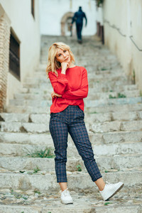 Happy young blond woman standing on beautiful steps in the stree