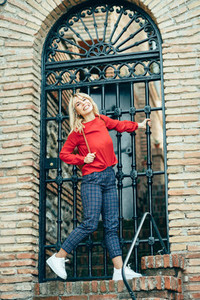 Happy young blond woman next to urban door