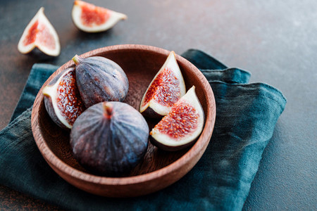 Macro photo of ripe quartes figs in a wooden small bowl on a table