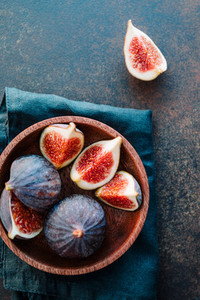 Top view of ripe quartes figs in a wooden small bowl on a table