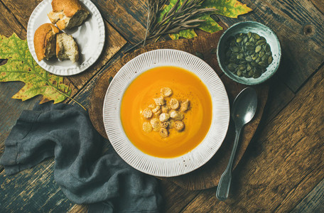 Warming pumpkin cream soup with croutons and seeds in plate