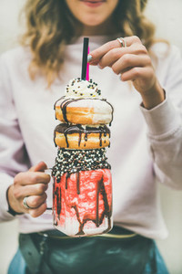 Girl holding cold strawberry donut freakshake in jar in hands