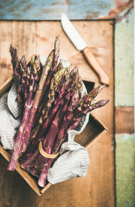 Fresh raw uncooked purple asparagus over rustic background  selective focus