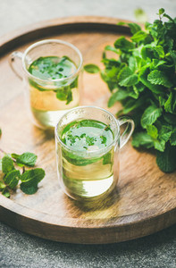 Hot herbal mint tea drink in glass mugs with leaves