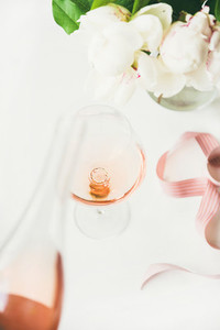 Rose wine in glass pink ribbon peony flowers on table
