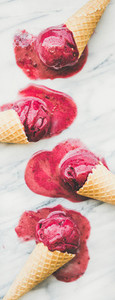 Raspberry sorbet ice cream scoops in waffle cones  close up  vertical composition