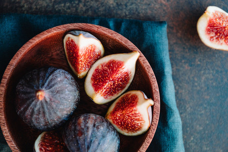 Top view of ripe figs in a wooden small bowl on a table