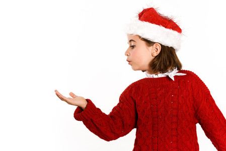 Adorable little girl wearing santa hat blowing to her hand