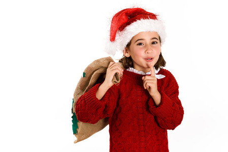 Adorable little girl wearing santa hat carrying gift bag