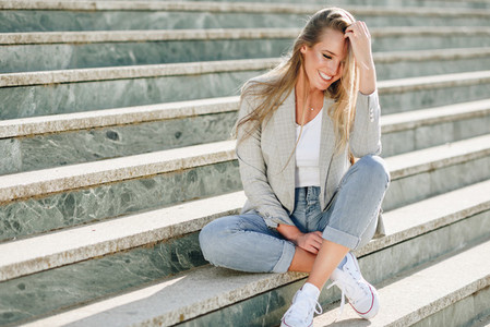 Beautiful young blonde woman smiling on urban steps