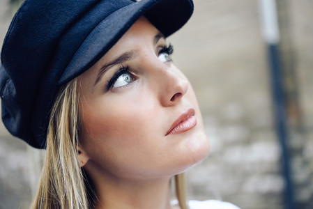 Young blonde woman wearing cap in urban background