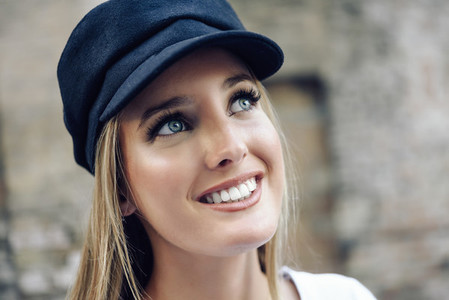 Young blonde woman wearing cap in urban background