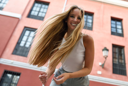 Happy young woman with moving hair in urban background