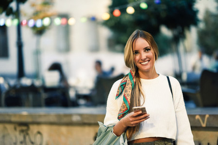 Woman with defocused urban city lights with smartphone