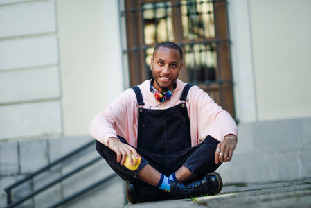 Young black man eating an apple sitting on urban steps