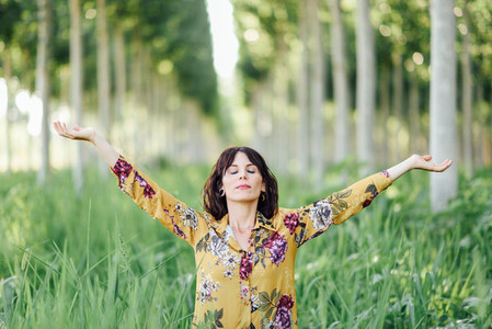 Woman arms raised enjoying the fresh air in green forest