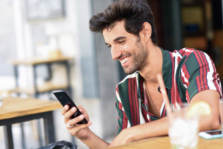 Young man using smartphone in an urban cafe