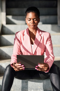 Black businesswoman sitting on urban steps working with a laptop computer