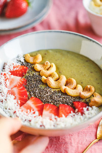 Green smoothie bowl with coconut cream  banana  strawberry  cashew and chia seeds  Healthy vegan eating