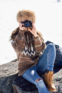 Young woman taking photographs in the snowy mountains
