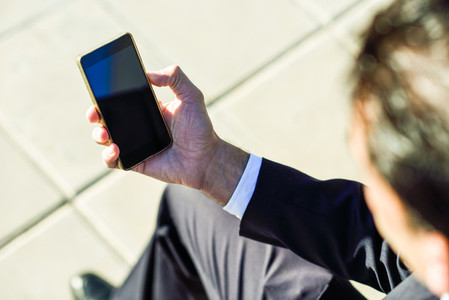 Businessman using his smartphone in the street